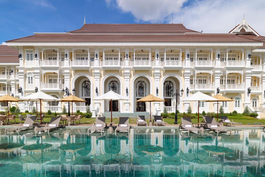 a large building with a swimming pool in front of it at Ping Pura Riverside Resort & Spa Chiang Mai in Chiang Mai