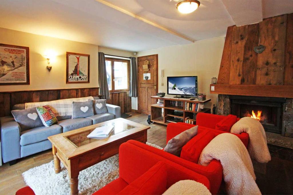 シャモニー・モンブランにあるLa Ferme des Praz apartment - Chamonix All Yearのリビングルーム(赤い家具、暖炉付)