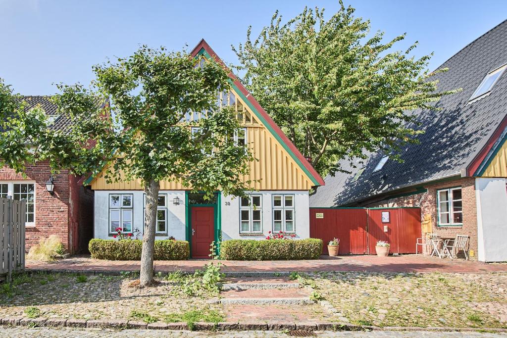 a house with a green door and a red fence at Altes Fährhaus - Ferienwohnung Unnern, 170 qm in Wewelsfleth