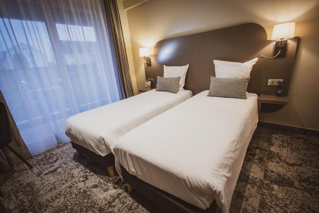 a hotel room with two beds and a window at Europe Haguenau – Hotel & Spa in Haguenau