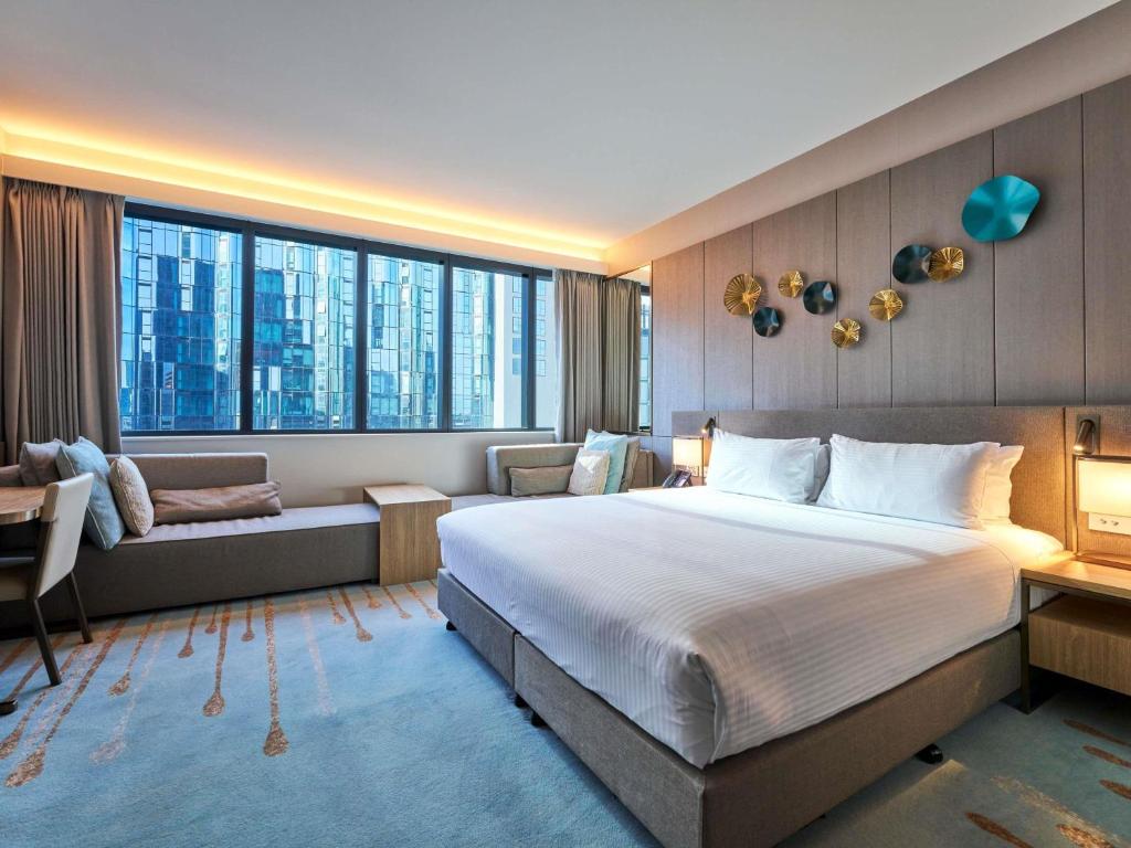 a hotel room with a large bed and a couch at Novotel Melbourne Central in Melbourne