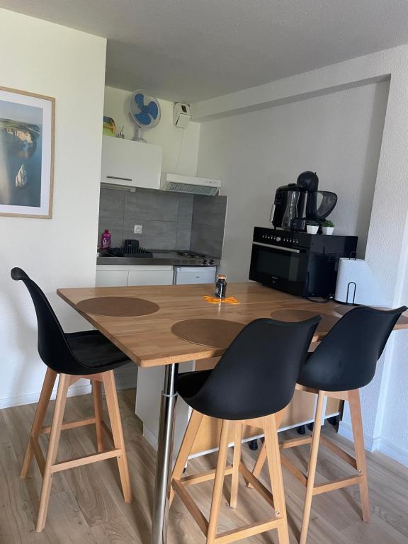 a kitchen with a wooden table and black chairs at Studio lumineux - Départs de randonnées in Laruns