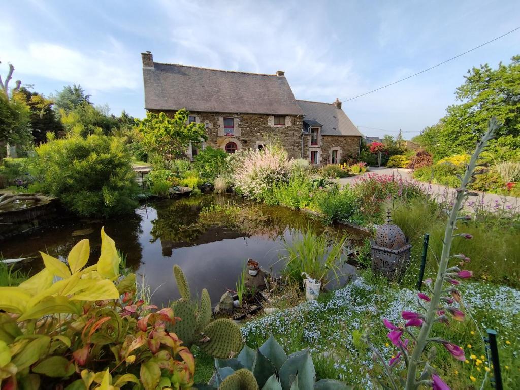a garden with a pond in front of a house at Gîte de la croix in La Croix-Helléan