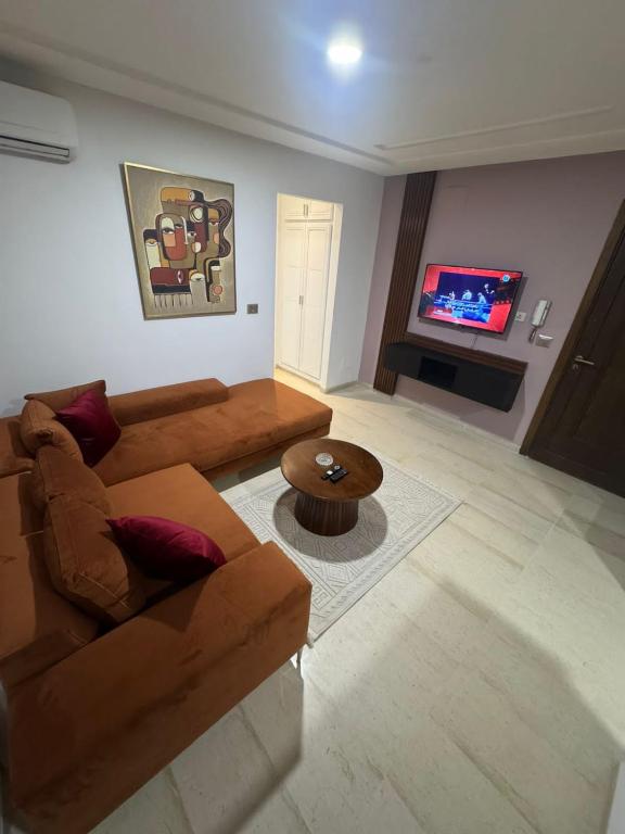 a living room with a brown couch and a table at Résidence les jasmins l''aouina in Tunis