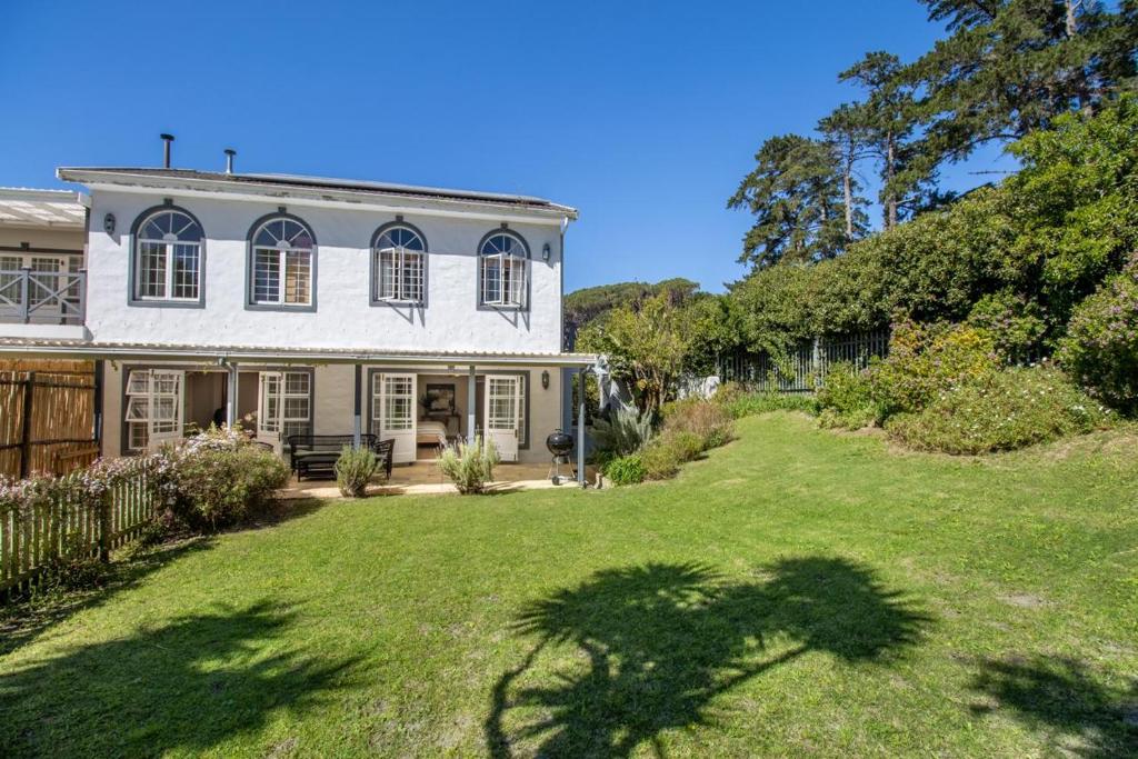 una grande casa bianca con un cortile erboso di Bloom Garden Cottage a Constantia