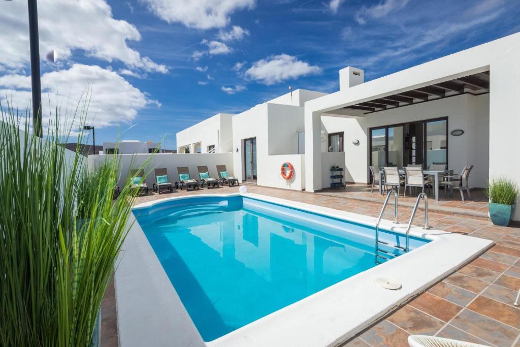 una villa con piscina di fronte a una casa di Villa Nayra a Playa Blanca
