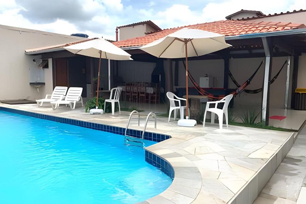 a house with a swimming pool with chairs and umbrellas at Casa no Centro de Pirenópolis in Pirenópolis