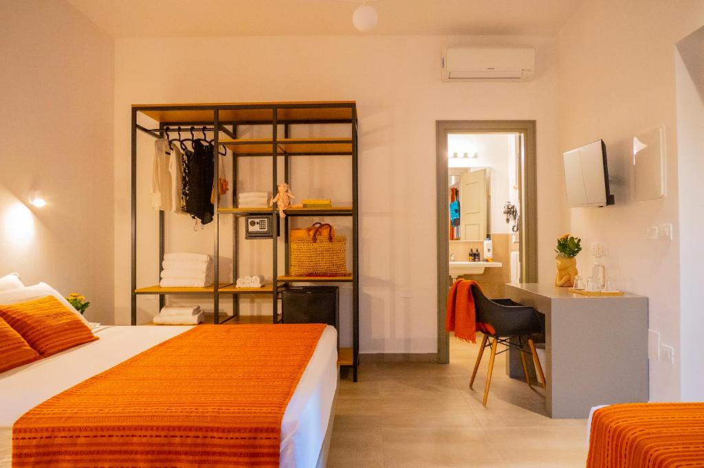 a bedroom with a bed and a desk and a kitchen at Policaretto Rooms by Calabria Stay in Torretta