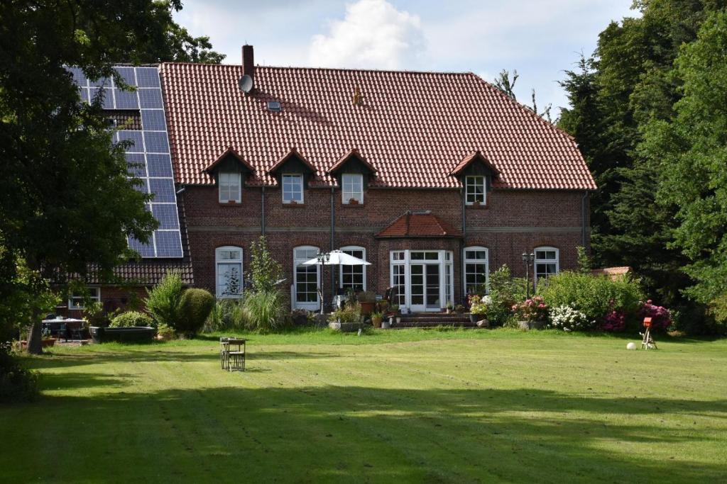 ein großes rotes Backsteinhaus mit einer Person im Hof in der Unterkunft Lüttje Paradies in Ruhwarden