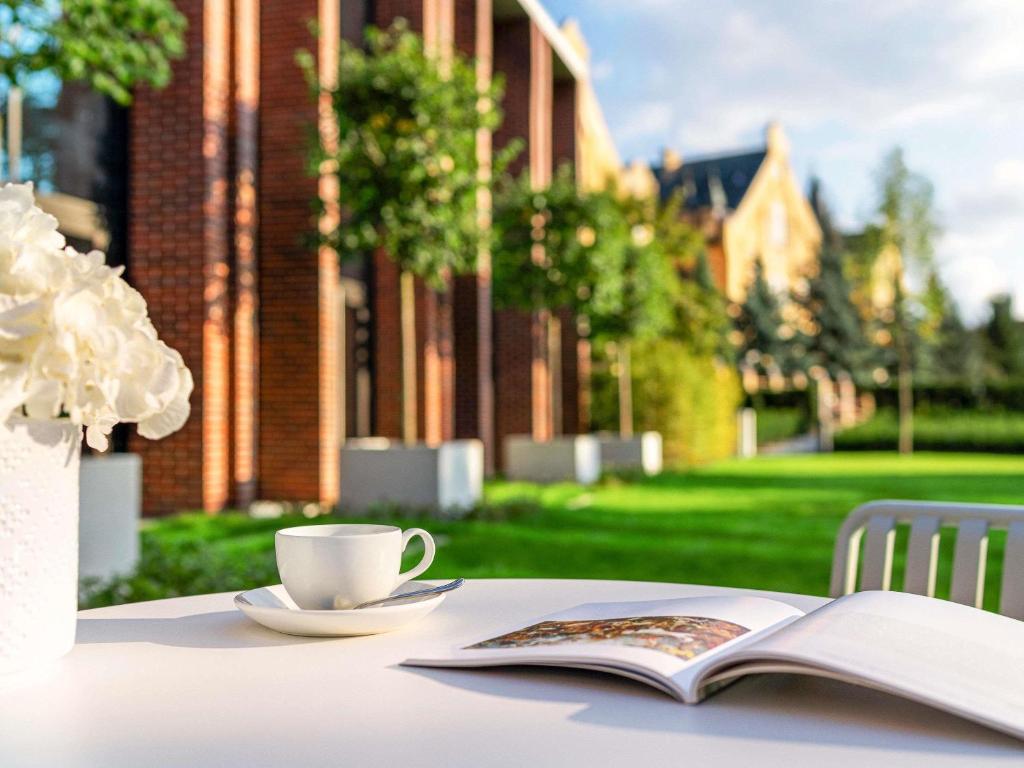 a table with a book and a cup of coffee and a book at The Bridge Wroclaw - MGallery in Wrocław