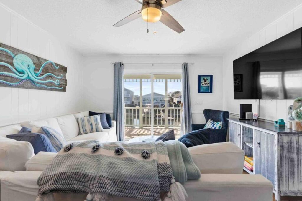 a living room with a couch and a ceiling fan at Pug Life - Walk to the Ocean in Ocean Isle Beach