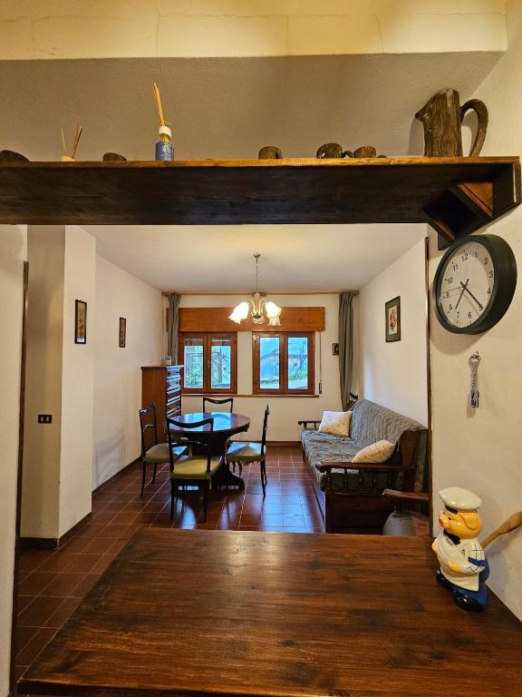 a living room with a table and a clock on the wall at Appartamento accogliente nel Cadore, 30 min Cortina in Pozzale