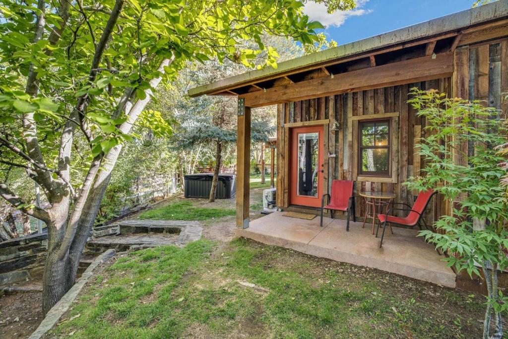 a cabin with red chairs and a table on a porch at Creekside Cowa-Bungalow - 61 E 200 - Studio in Moab