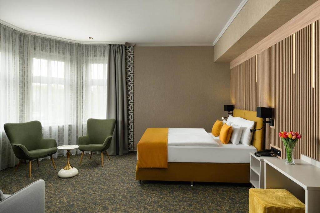 ein Hotelzimmer mit einem Bett und zwei Stühlen in der Unterkunft Hotel Allora in Budapest