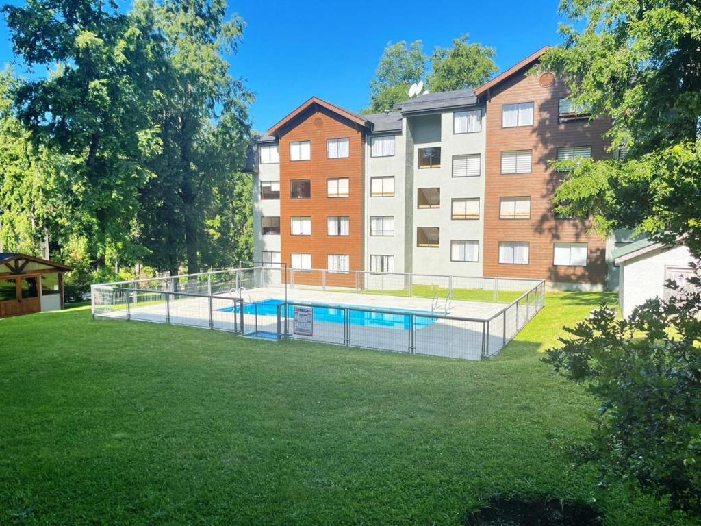 a swimming pool in a yard in front of a building at Refugio del volcán in Pucón