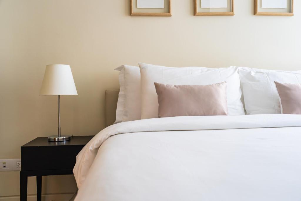 a white bed with white pillows and a table with a lamp at Dorma Coliseum in Santander