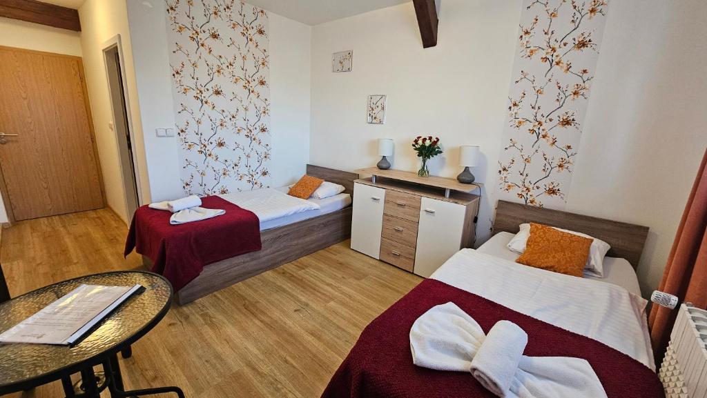 a room with two beds and a table and a table at Penzion Alfa Poděbrady in Poděbrady