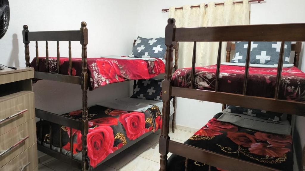 瓜拉廷格塔Chácara charmosa com piscina, campo de futebol的一间卧室配有两张双层床,铺有红色床单