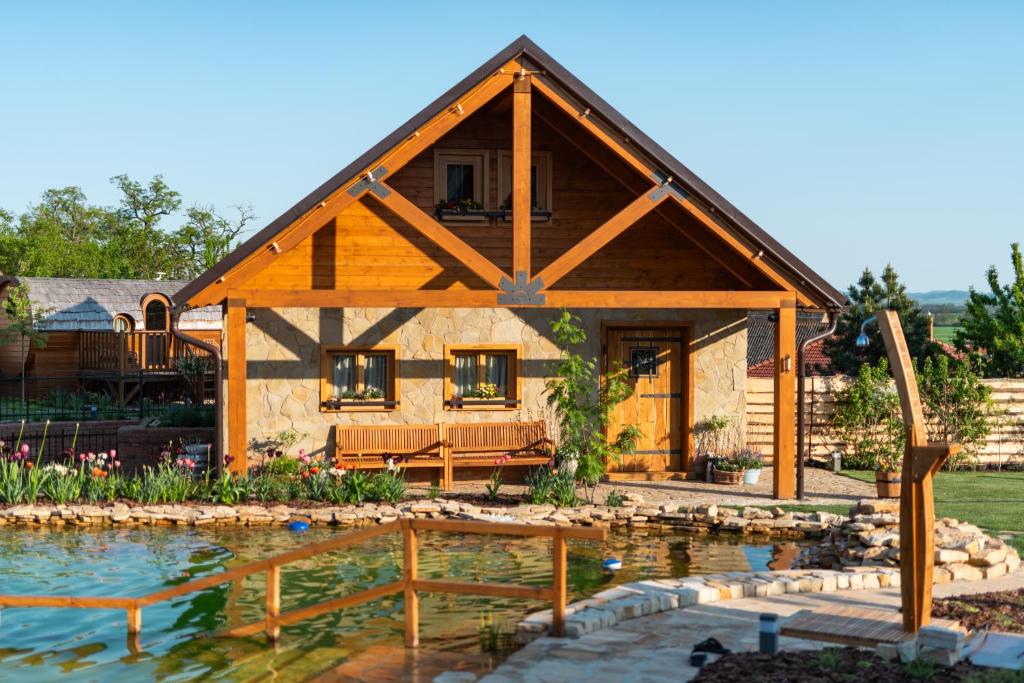 a log home with a pond in front of it at Wellnes Hříbek in Dyjákovice