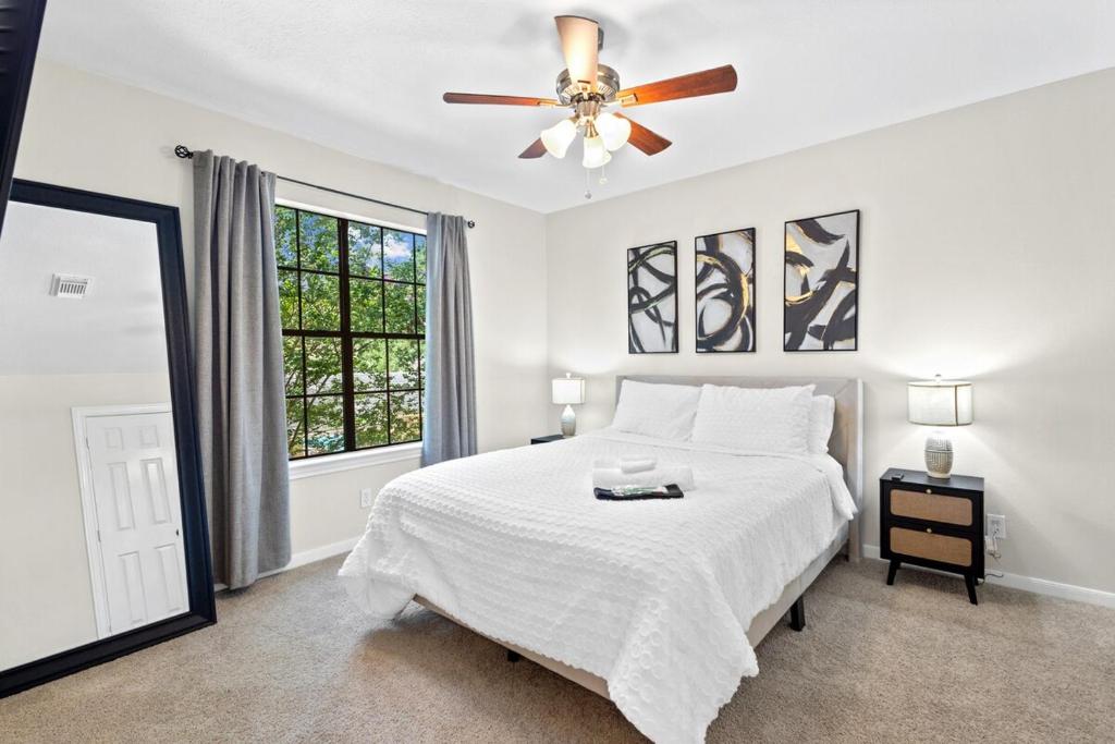 a white bedroom with a bed and a ceiling fan at Luxe House Houston in Houston