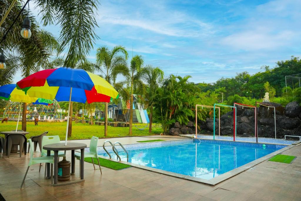 a table with an umbrella next to a swimming pool at Rio Royale in Bhimashankar