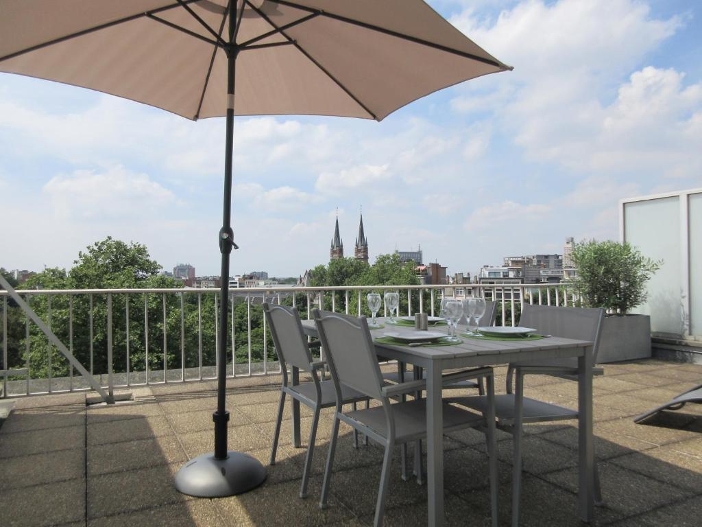 un tavolo e sedie con ombrellone su un balcone di Fuths Loft Penthouse 85 ad Anversa