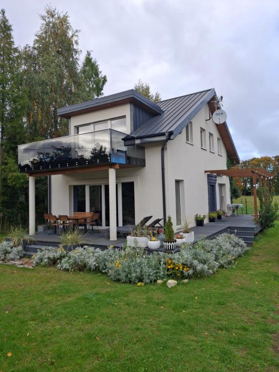 a white house with a deck with a table and benches at Villa Helena in Nowe Warpno