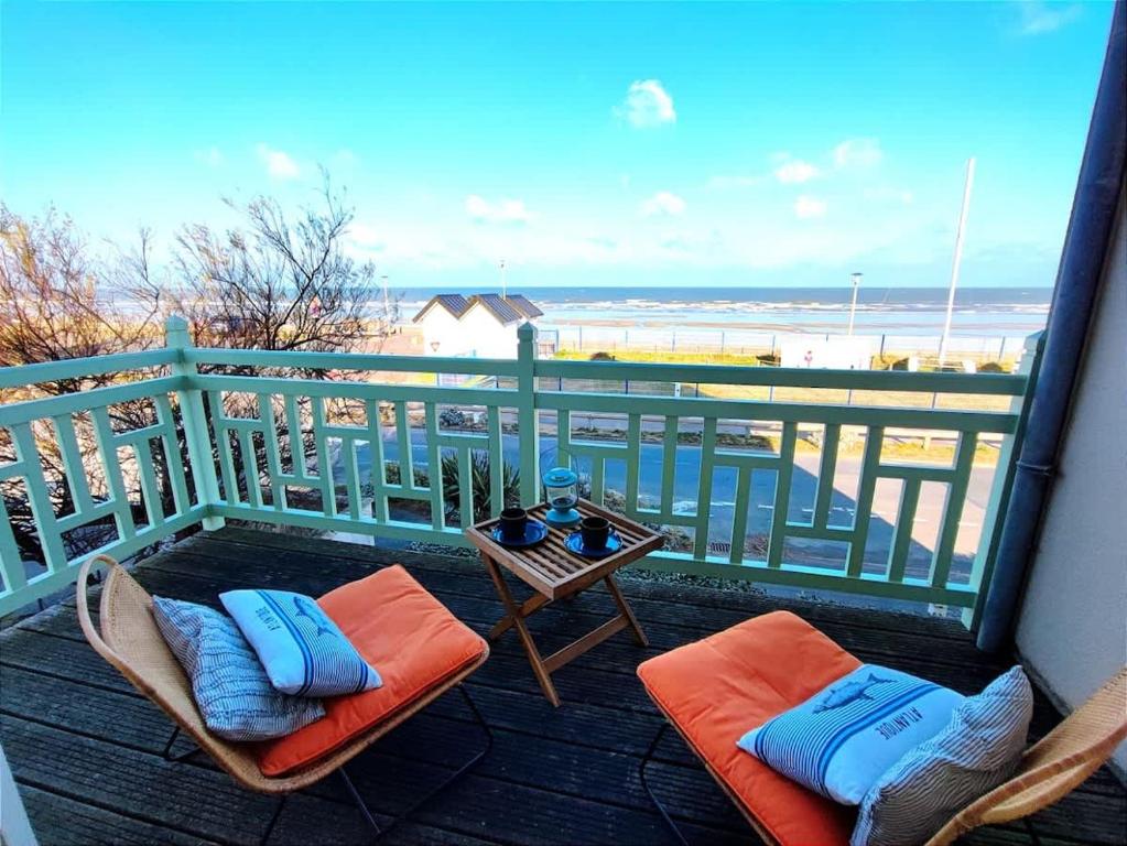 een balkon met stoelen en een tafel met uitzicht op het strand bij Villa Bellevue - Anglo-Norman seafront house in Ouistreham