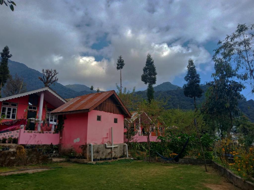 a small pink house with mountains in the background at Welcome homestay in Pemayangtse