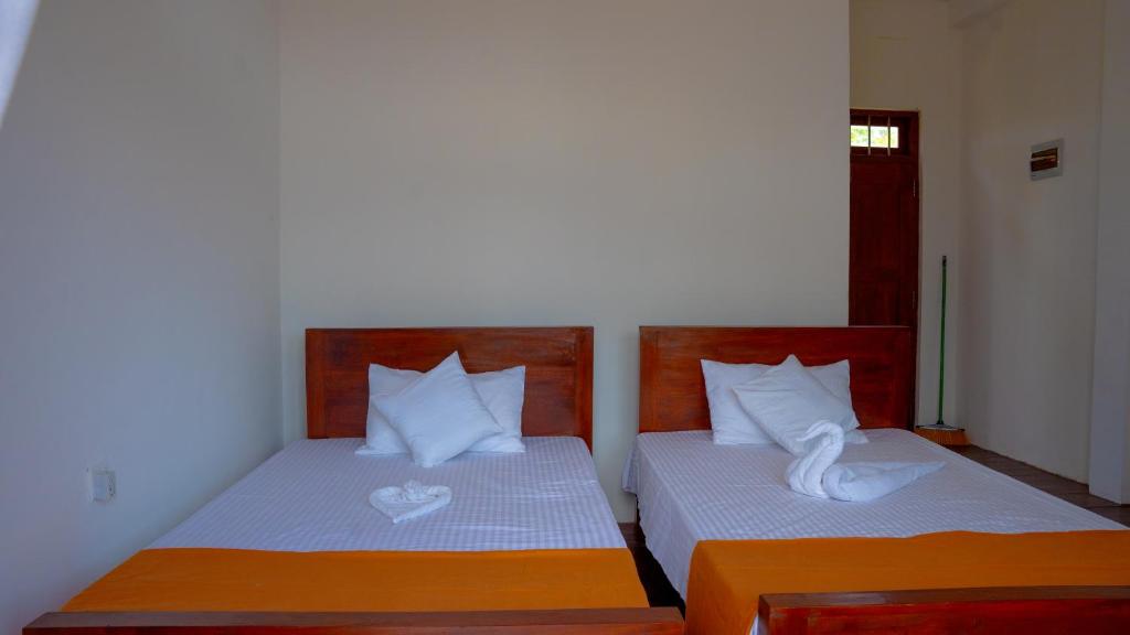 a bedroom with two beds with white pillows at Diamond Mount Villa in Dambulla