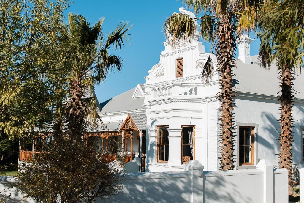 a white house with palm trees in front of it at Old Posthouse Guest Accommodation in Ladismith