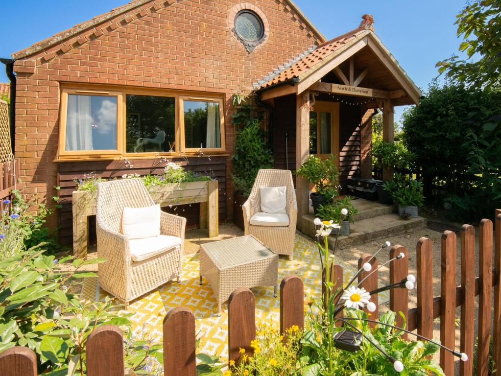 a patio with wicker chairs and a table at 1 Bed in Horningtoft 91344 in Whissonsett