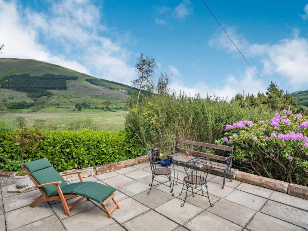 un patio con sillas, un banco y flores en 1 Bed in Callander PE173, en Strathyre
