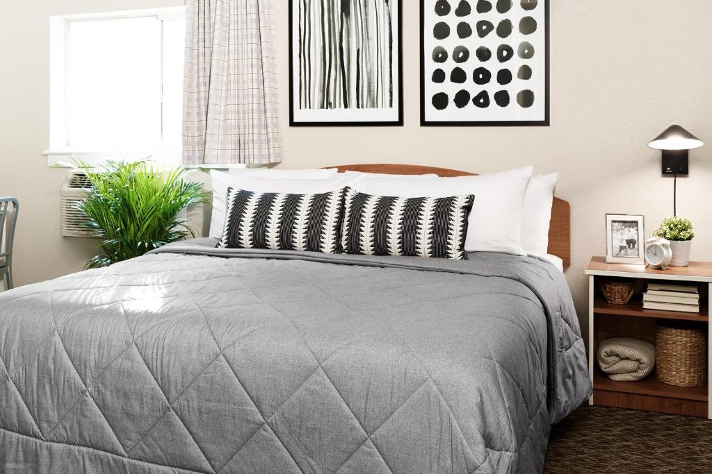 - une chambre avec un lit et une couette grise dans l'établissement InTown Suites Extended Stay Dothan AL, à Dothan