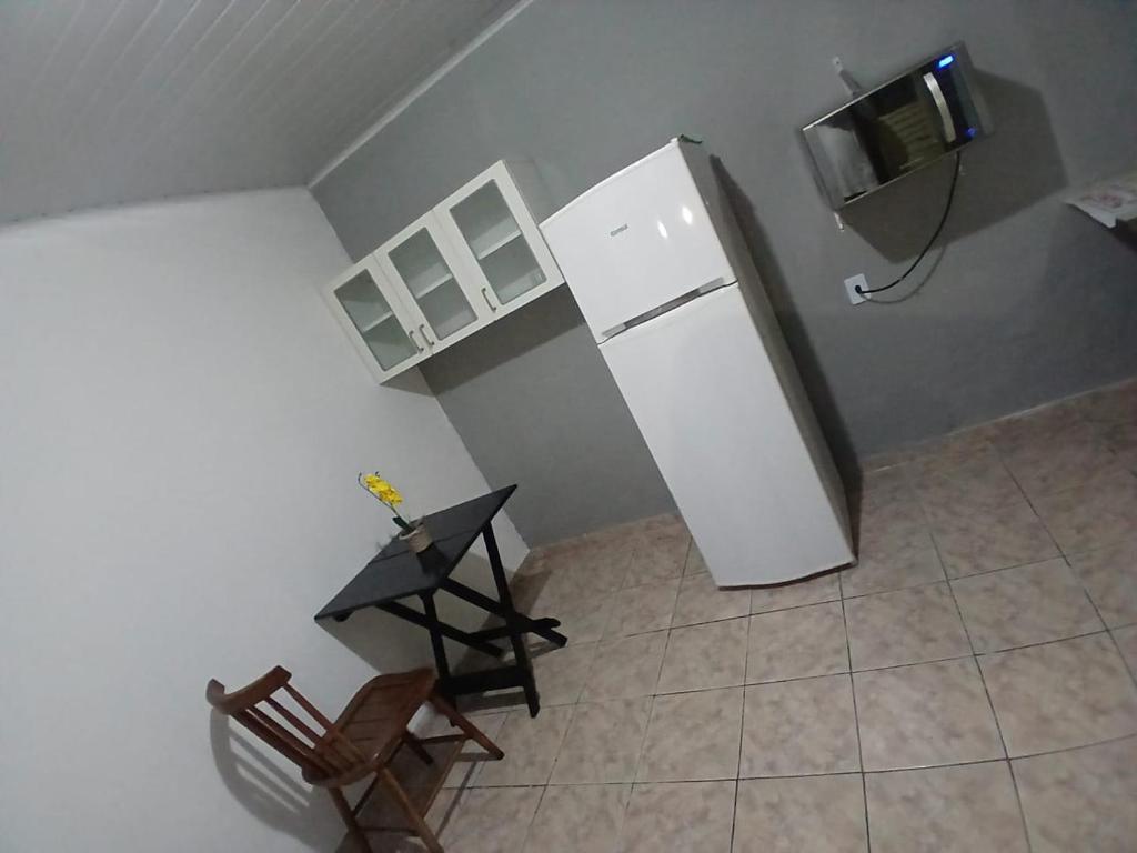 a kitchen with a refrigerator and a table and a chair at Pousada conti viracopos in Campinas