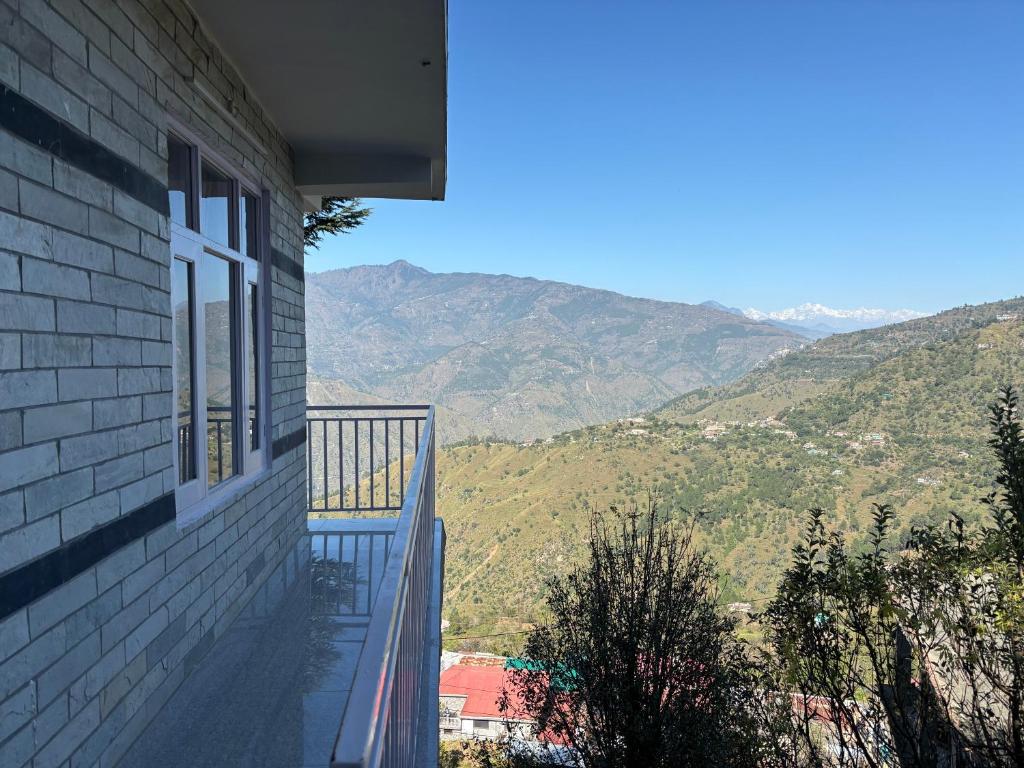 a balcony of a house with a view of mountains at Sunrise View Farm-stay -Narkanda in Shimla