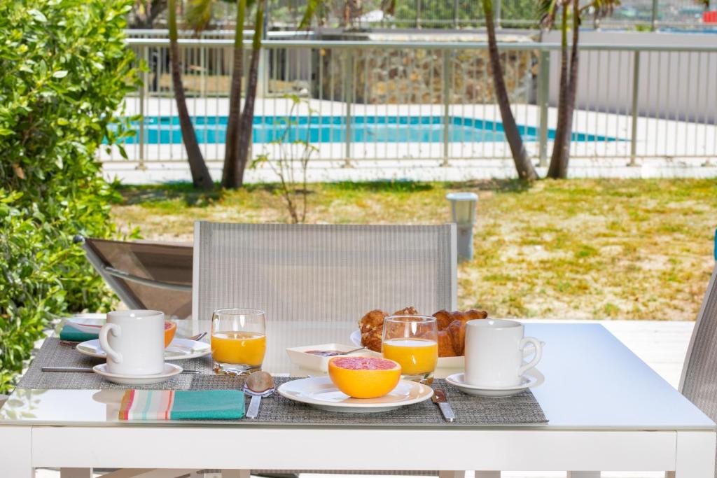 a table with breakfast foods and orange juice on it at SALT 6 Sur la plage de la BaieOrientale, appart 1ch in Orient Bay