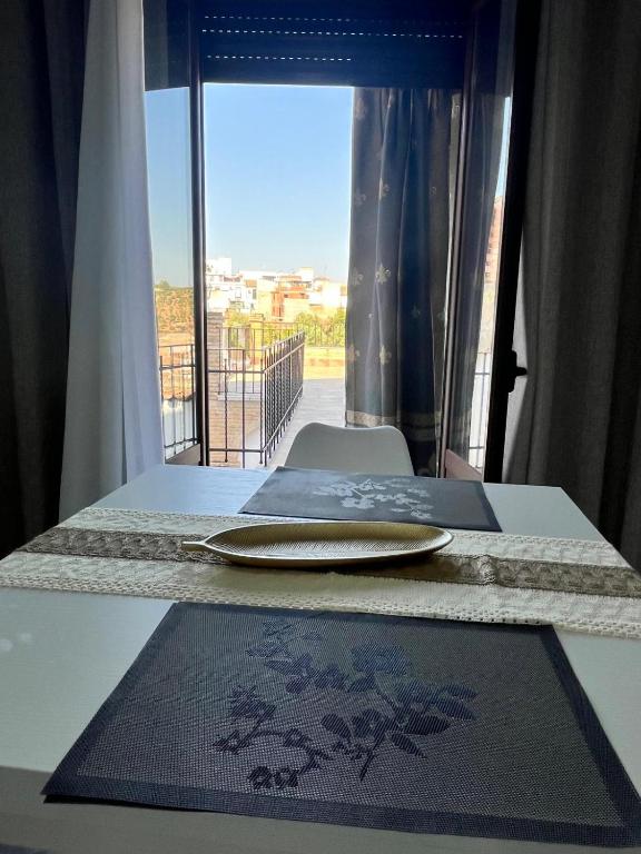 a table with a plate on a table with a window at Apartamento El Rincón del Olivar III in Montoro