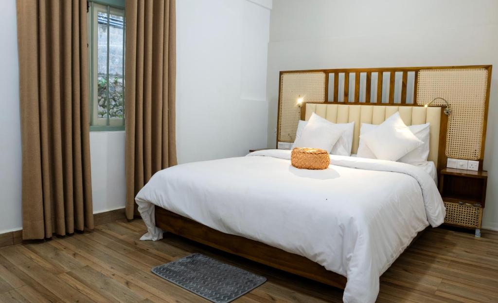 a bedroom with a large white bed and a window at The Living Villa in Badulla