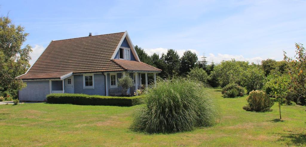 a small blue house in a field of grass at Between the dunes and the sea in Les Moitiers-dʼAllonne