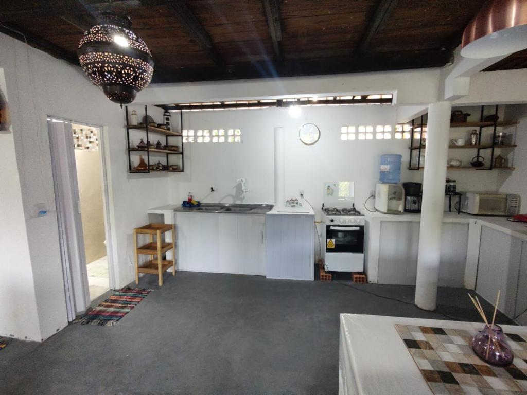 a large kitchen with white counters and aendant light at Chalé Maison Blanche in Maracanã
