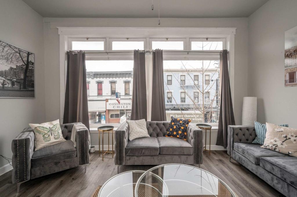 a living room with two couches and a large window at The Heart of Madison Suites in Covington