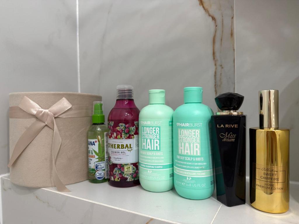 ein Regal mit vier Flaschen Haarpflegeprodukten und einer Schachtel in der Unterkunft Golden Eden Wieniawska - Rezydencja Ogród Saski in Lublin