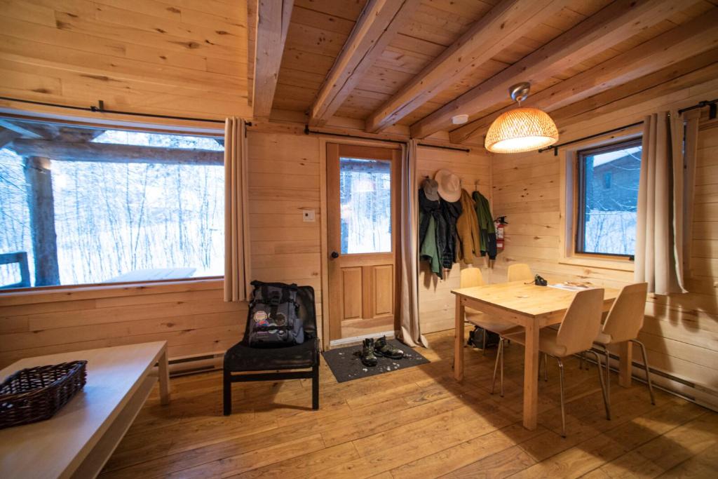 een eetkamer met een tafel en stoelen in een hut bij Huttopia Les Deux Lacs - Laurentides in Saint-Faustin
