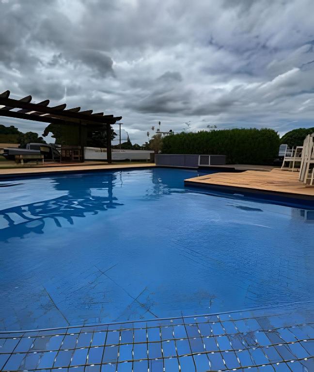 a large blue swimming pool with a pergola at Chácara c/piscina, área para eventos e 4 quartos in Ribeirão Preto