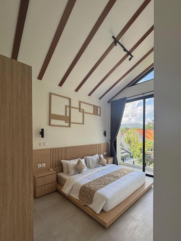 a bedroom with a large bed and a large window at LM Home 2 Mendira in Candidasa