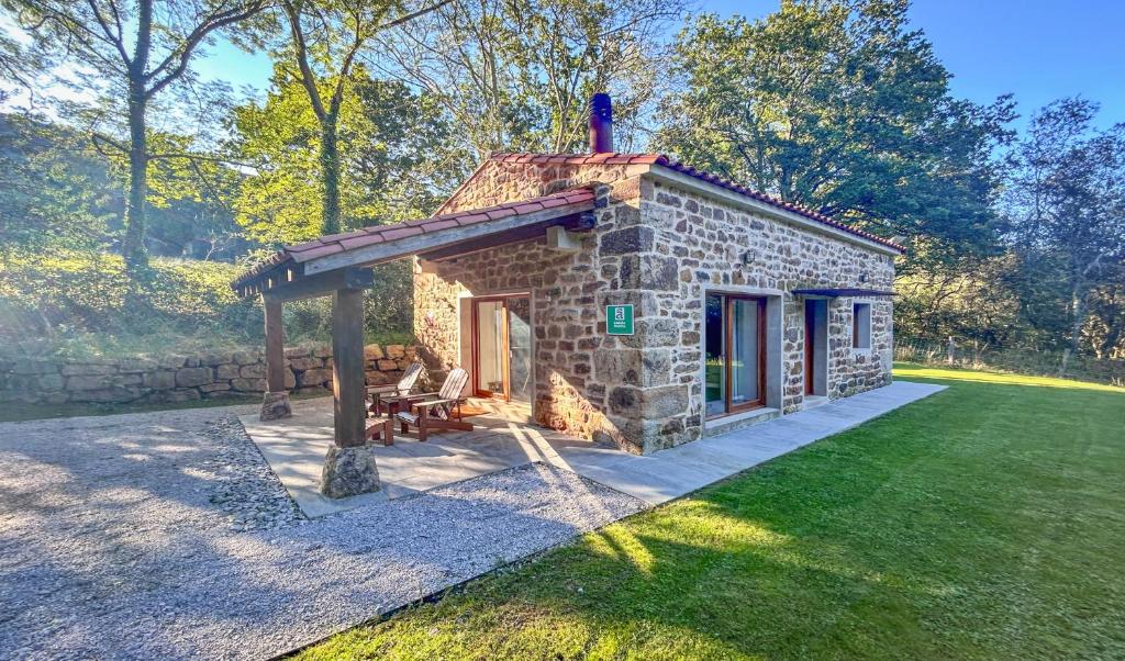 a small stone building with a porch on a lawn at Cabaña Quieva 03 in Rubalcaba