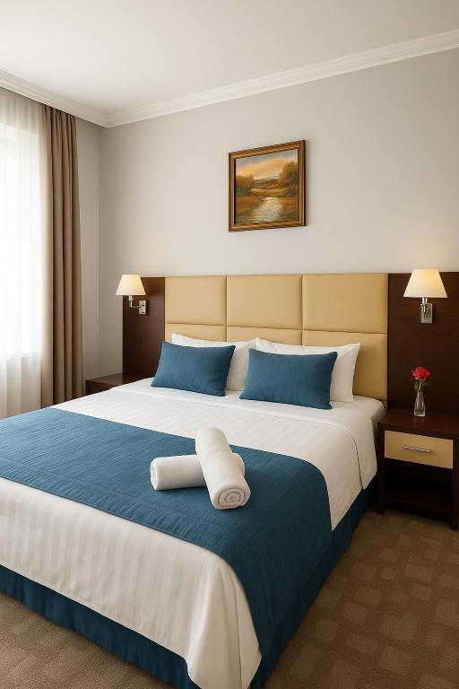 Un dormitorio con una cama grande con almohadas azules. en Tanzharyk Hotel, en Aktobe