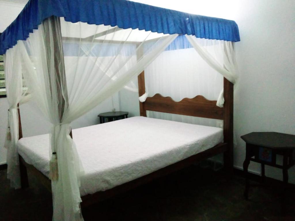 Un dormitorio con una cama con dosel y una mesa. en Allison Homes, en Kilifi