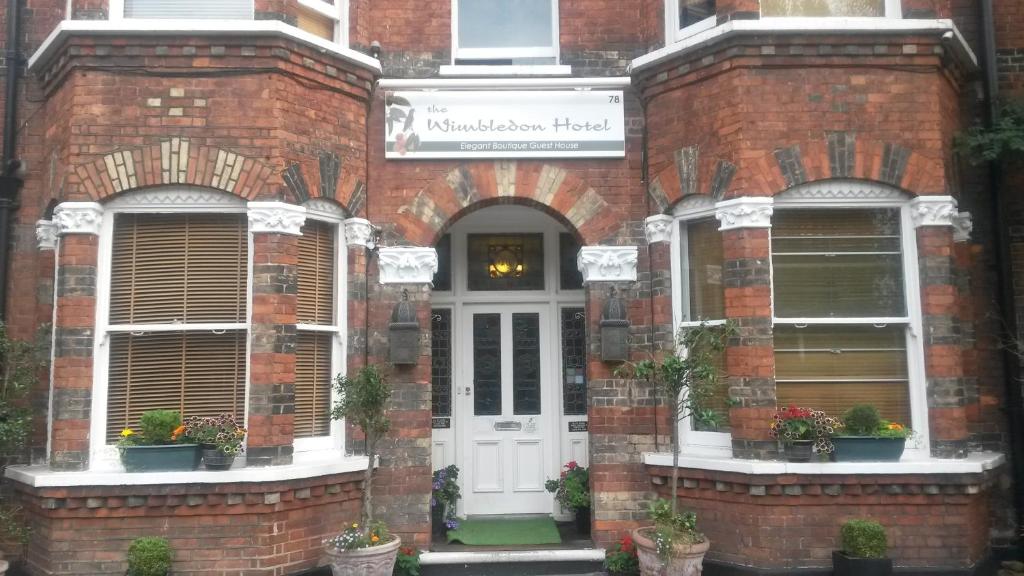 ceglany budynek z białymi drzwiami i roślinami w obiekcie The Wimbledon Hotel w Londynie